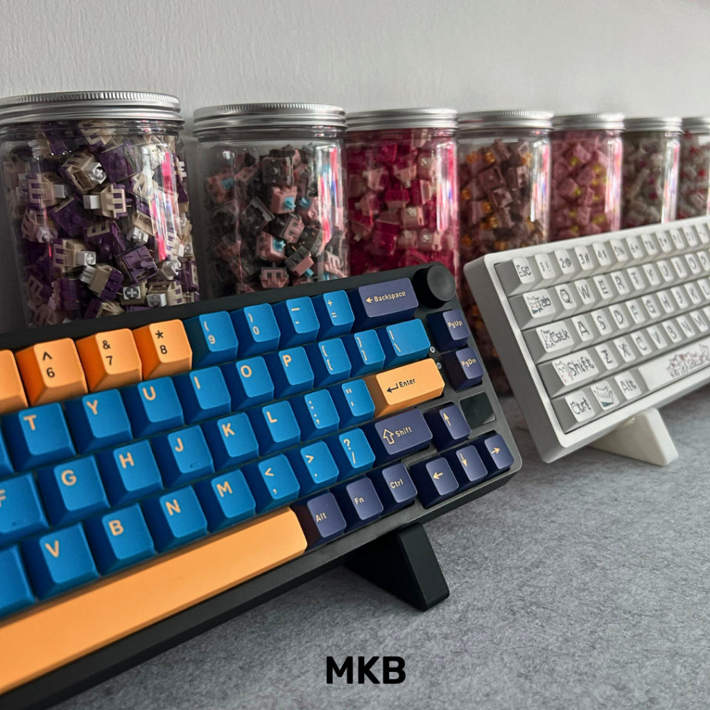 A white and a black MKB Keyboard Stand holding a mechanical keyboard respectively