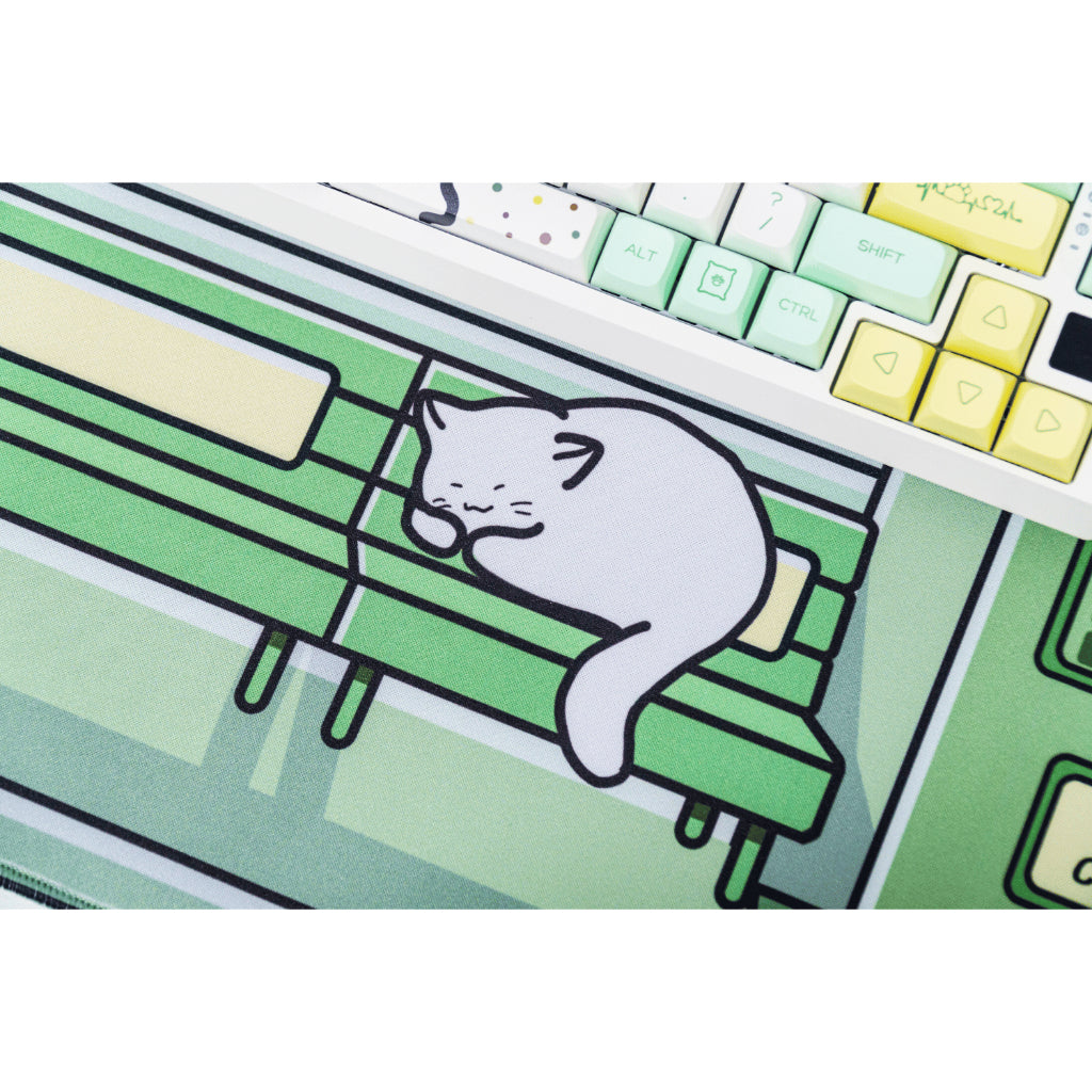 Green deskmat featuring a cat sleeping on the bench