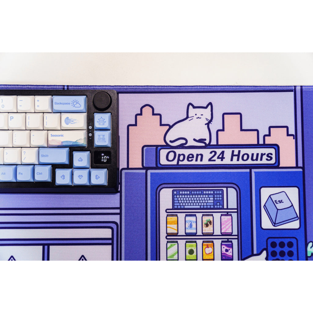 A black keyboard placed beside a blue deskmat