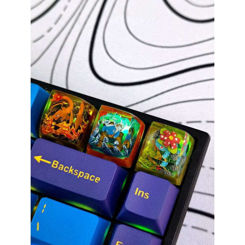 3 Pokemon Artisan Keycaps mounted on a keyboard. Charizard Artisan Keycap sitting on a backlit keyboard, showcasing its shine-through effect.